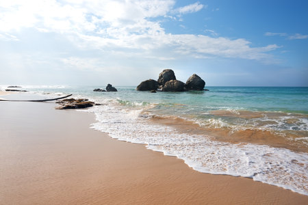Heap of stones in ocean near sandy beachの写真素材