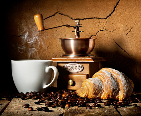 Fresh croissant and coffee grains on wooden tableの写真素材