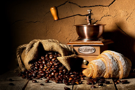 Grains of coffee with coffeemill and croissantの写真素材