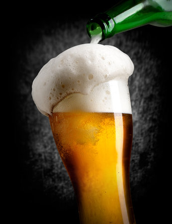 Beer pouring into glass on black backgroundの写真素材