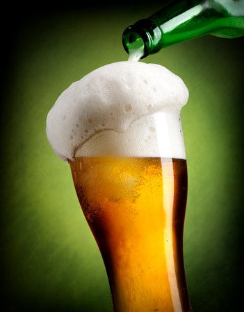 Beer pouring into glass on green backgroundの写真素材