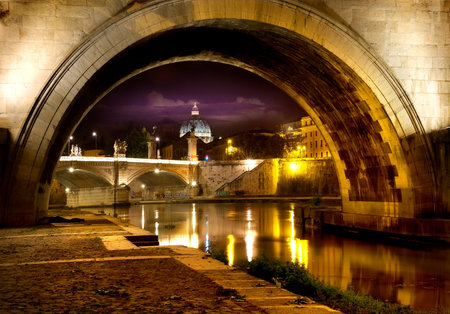 Night view on the Sant Angelo Bridge and Basilica of St. Peter in Rome, Italyの写真素材