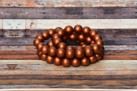 Necklace made of plastic shaped small brown balls arranged lengthwise above the board