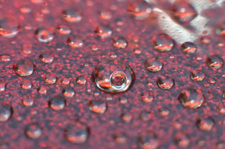 shiny clear water point attached to a glass reflects the same color as the color on the glass into a...