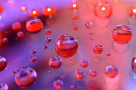 shiny clear water point attached to a glass reflects the same color as the color on the glass into a...