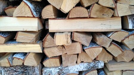 Chipped firewood is on the heap. Woodpile of firewood close-up. A stack of dry firewood, visible texture and cracks in the tree. Exterior shot of a large pile of firewood in soft daylightの写真素材