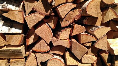 Chipped firewood is on the heap. Woodpile of firewood close-up. A stack of dry firewood, visible texture and cracks in the tree. Exterior shot of a large pile of firewood in soft daylightの写真素材