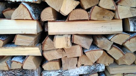 Chipped firewood is on the heap. Woodpile of firewood close-up. A stack of dry firewood, visible texture and cracks in the tree. Exterior shot of a large pile of firewood in soft daylightの写真素材