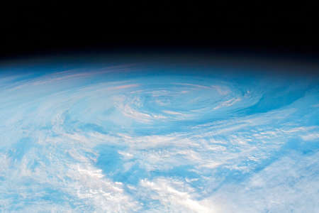South Pacific Swirl, circular cloud formation photo from space, swirling clouds in the sky image, light blue and white cluodscape on a black background spaceの写真素材