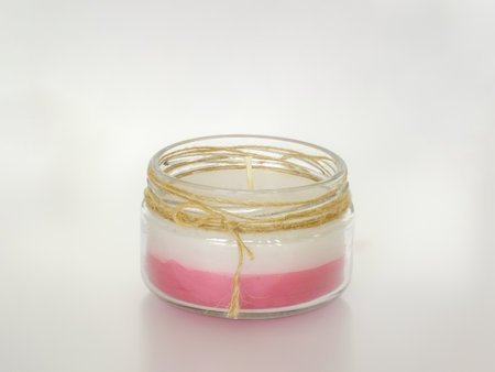 Homemade candle in a glass jar isolated on white background. Handmade candle in pink and white.の写真素材