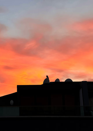 Dramatic sunset sky with shadow of an apartment building roof with a crowの写真素材