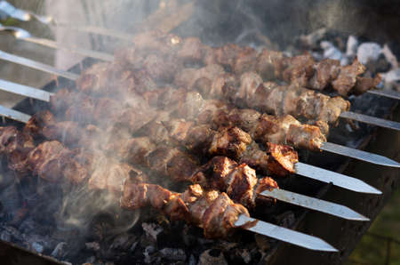 Pork shish kebab is cooked on the grill. Smoke from coalsの写真素材
