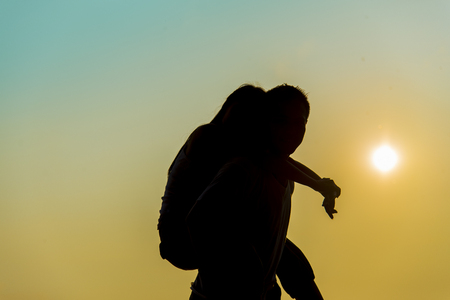 Lovely Couple piggy back ride on sunset in Silhouette  sceneの写真素材