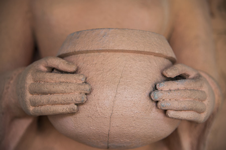 Hands hold alms bowl of buddha statueの写真素材