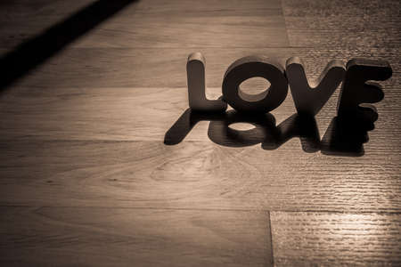 Wooden word LOVE on laminate floor in shadow shade styleの写真素材