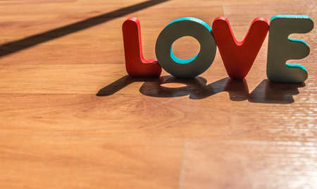 Wooden word LOVE on laminate floor in shadow shade styleの写真素材