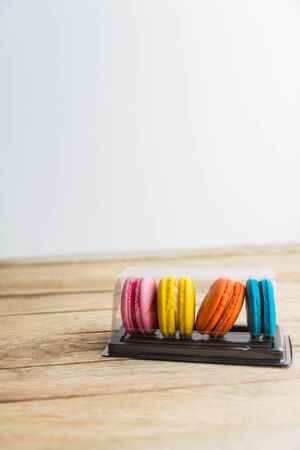 Colorful macaron in plastic box on wooden floorの写真素材
