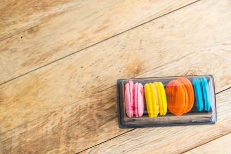 Colorful macaron in plastic box on wooden floor