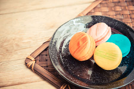 Colorful macaroons in black dish on wooden floor in Vintage themeの写真素材