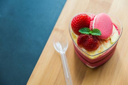 Strawberry moose cake with macaron on wooden plateの写真素材
