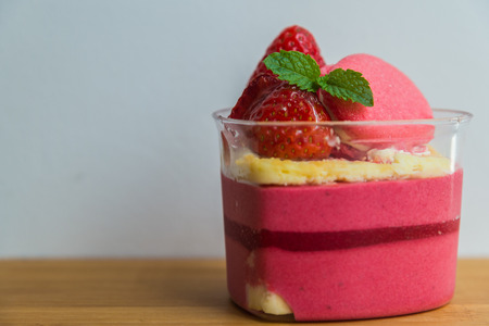 Strawberry moose cake with macaron on wooden plateの写真素材