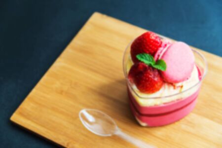 Strawberry moose cake with macaron on wooden plate in Blur styleの写真素材
