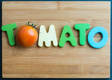 Tomato wooden word on chopping block