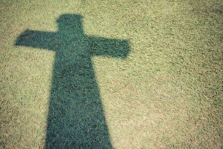 Shadow of Christian cross on green grass floor with Vintage filter styleの写真素材