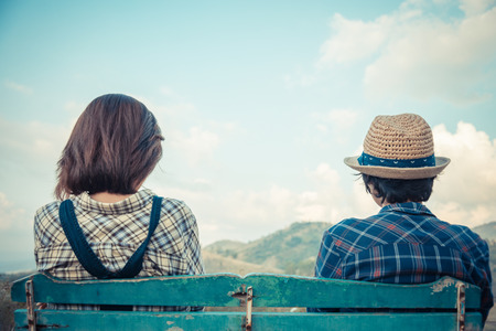 Back side of lovely couple sit on wooden chair with sky viewの写真素材