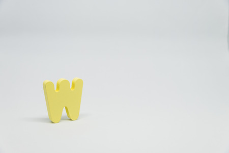Yellow Wooden alphabet W with white backgroundの写真素材