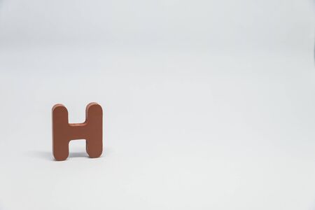 Brown Wooden alphabet H with white backgroundの写真素材