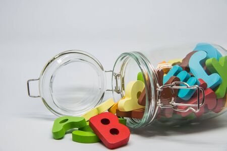 Colorful Wooden alphabet over the glass bottle with white background in Horizontal view and selective focusの写真素材