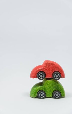 Red toy car overlay on green toy car with white background and selective focus