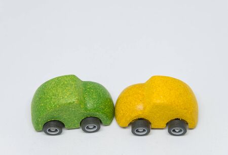 Green toy car accident crashed yellow toy car with white background and selective focusの写真素材