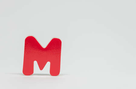 Red wooden alphabet M with white background and selective focus