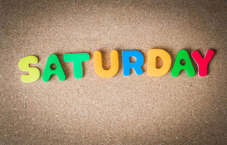 Colorful wooden word SATURDAY on Cork board with selective focusの写真素材
