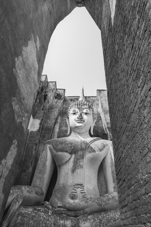 Black and white view of Old sitting buddha statue through the gate of ancient temple Thailandの写真素材