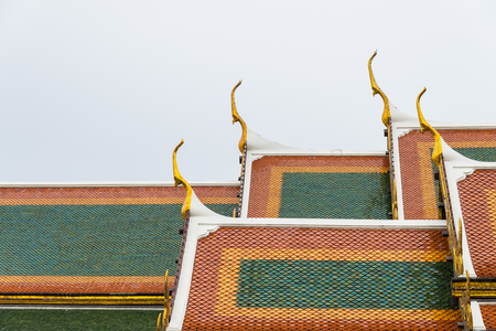 Ceramic roof tile temple in Thailand with cloudy skyの写真素材