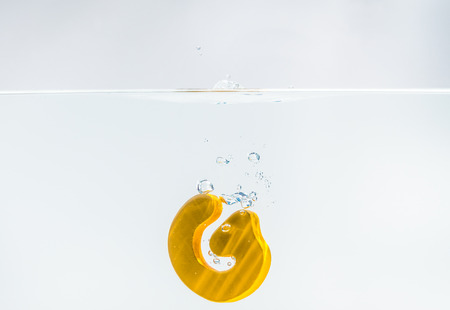 Yellow wooden alphabet G drop in the water with white background and selective focusの写真素材