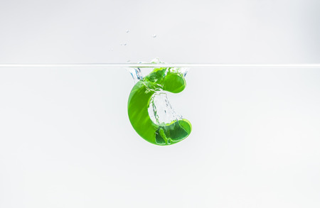 Green wooden alphabet C drop in the water with white background and selective focusの写真素材