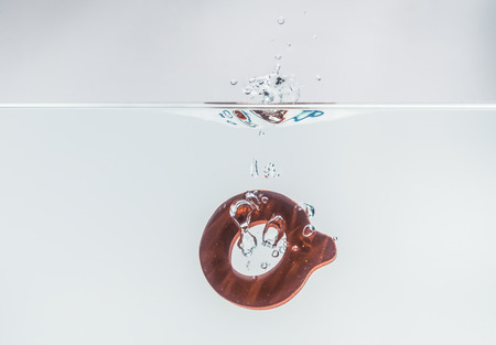 Brown wooden alphabet Q drop in the water with white background and selective focusの写真素材