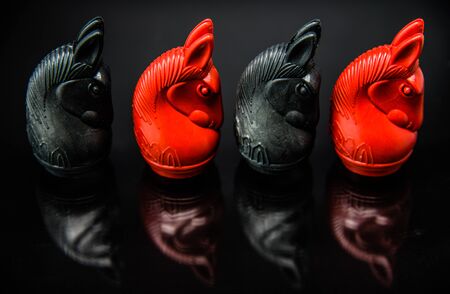 Sequence of Red and Black Knight Thai chess pieces with black background and selective focusの写真素材