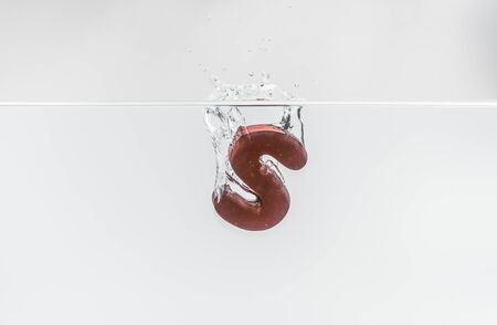 Brown wooden alphabet S drop in the water with white background and selective focusの写真素材