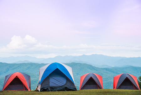 Four camping tent set on grass floor with beautiful view of Green mountain backgroundの写真素材