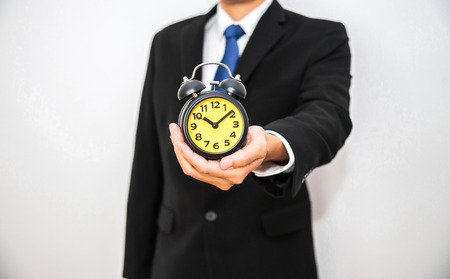 Business man hold black alarm clock on hand with isolated white backgroundの写真素材