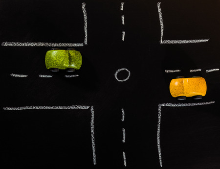 Green and Yellow wooden car toys stop on crossroad on chalk board