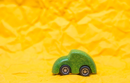Isolated Green wooden car toy on Yellow crumpled paper backgroundの写真素材