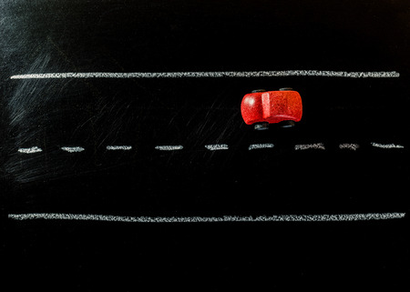 Red wooden car toy on the road of chalk boardの写真素材