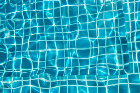 Blue ripple wave water in Swimming pool with sun reflection in background concept