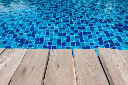 Blue ceramic floor in swimming pool with wooden floor in background concept